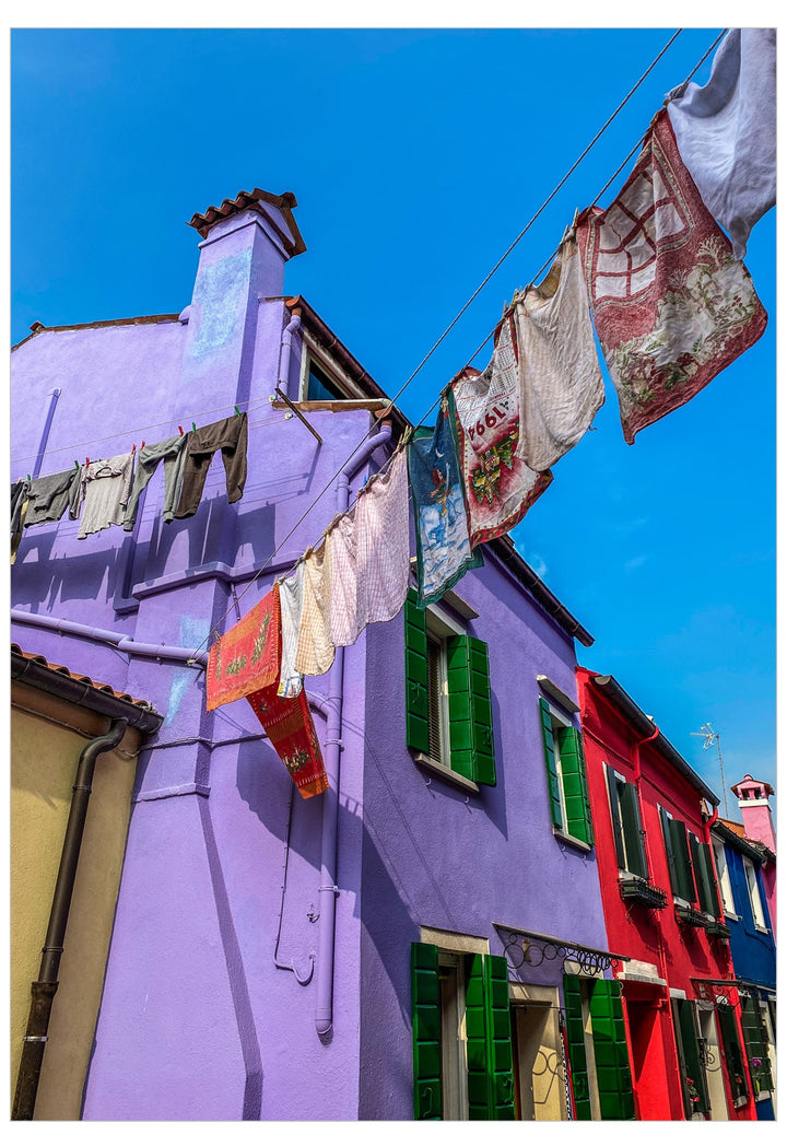 Colorful Italian-style buildings under a bright blue sky, with laundry hanging on clotheslines across the scene.