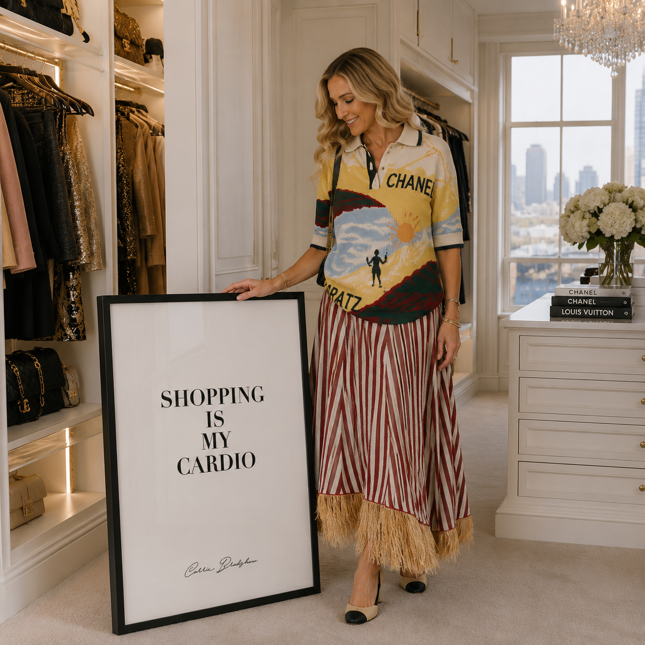 A woman stands in a luxury dressing room holding a large framed art print that reads 'SHOPPING IS MY CARDIO' with a black signature at the bottom. 