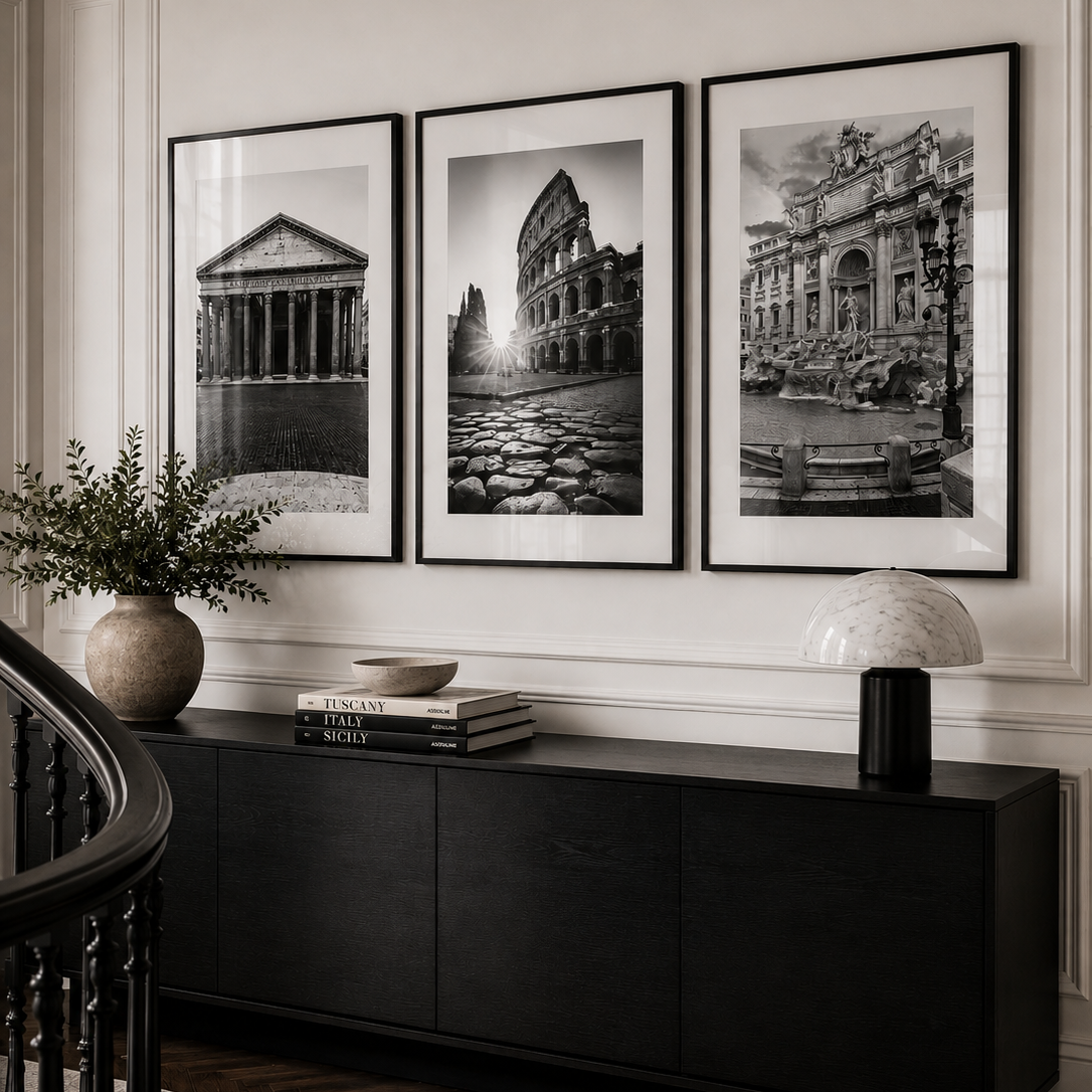 Three framed black and white architectural art prints are displayed on a white paneled wall above a dark wood console table in a styled interior room.