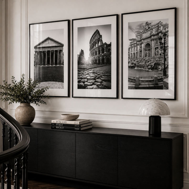 Three framed black and white architectural art prints are displayed on a white paneled wall above a dark wood console table in a styled interior room.