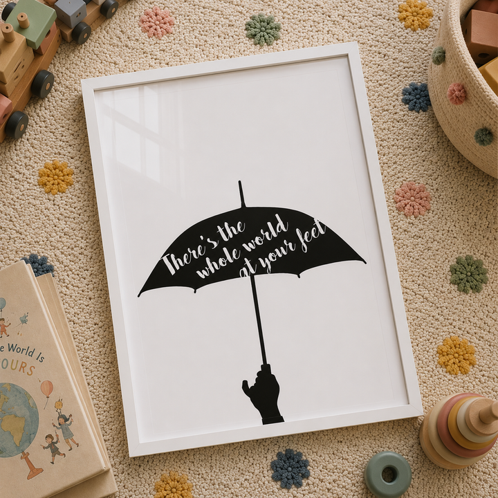 A framed art print featuring a black umbrella silhouette with the hand-lettered quote 'There's the whole world in your hand' on a white background, styled in a cozy children's room setting with toys and textured rugs.