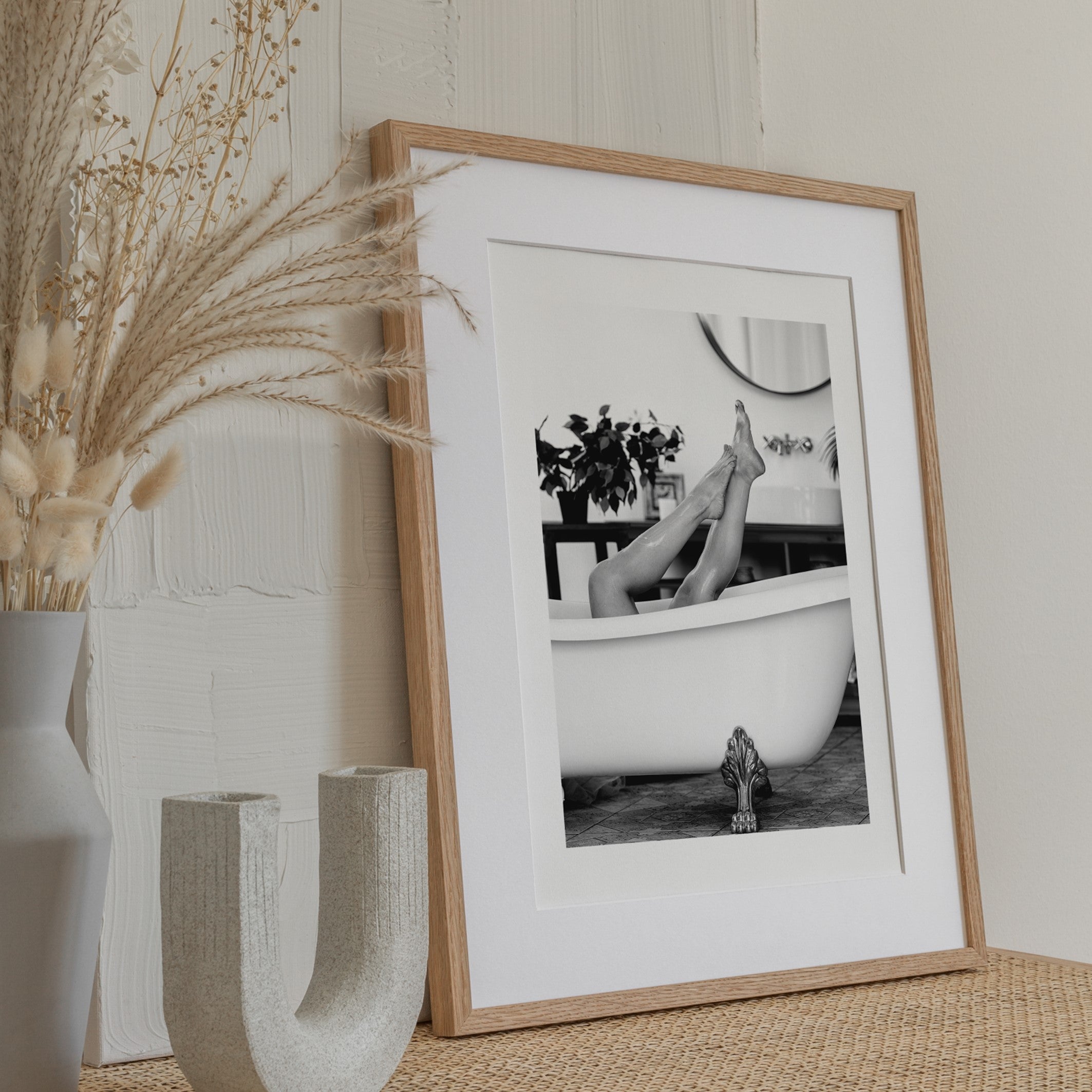 Framed Bathroom poster of a womans legs in the air, laying in a roll top bath with iron claw foot legs. 